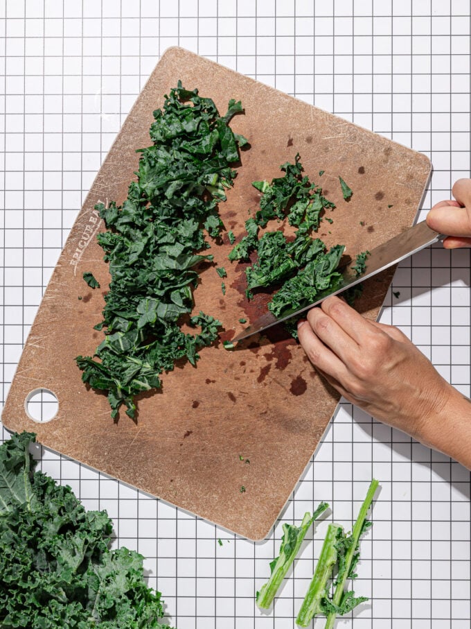 hand slicing kale on cutting board