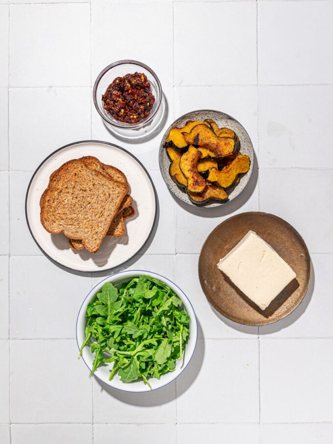 plates of feta cheese, arugula, roasted squash, toast