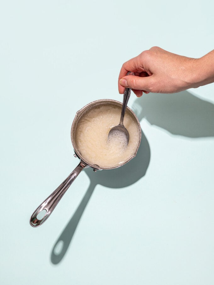 hand stirring melted coconut oil in pot